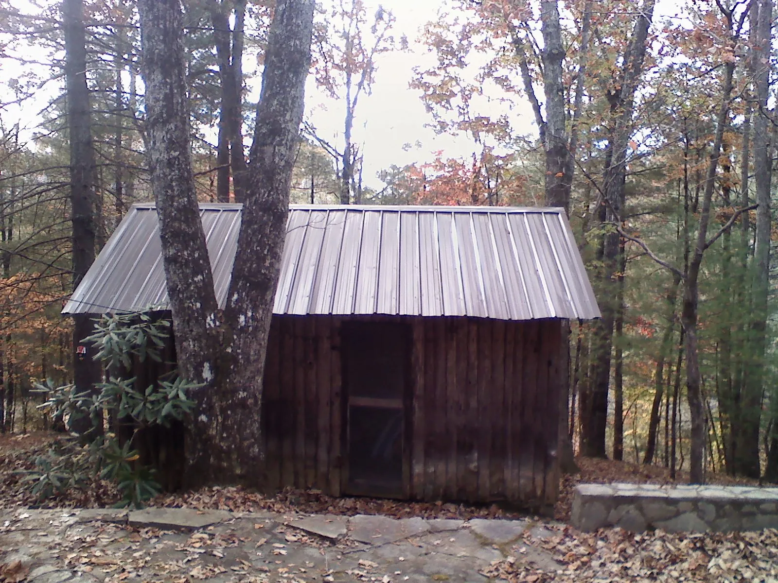 New metal gable roof on a small log shed among the trees in Union